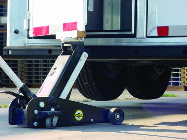 A Cimarron trailer being lifted by a jack resting on its heavy duty door.